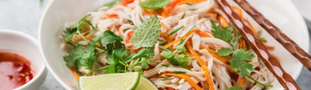 chicken, rice noodle and carrot salad in white bowl with sweet chili sauce, selective focus
