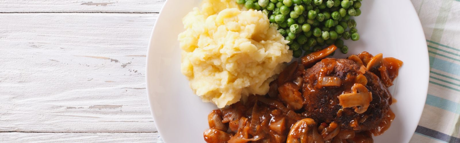 Salisbury steak with gravy, mashed potatoes and green peas